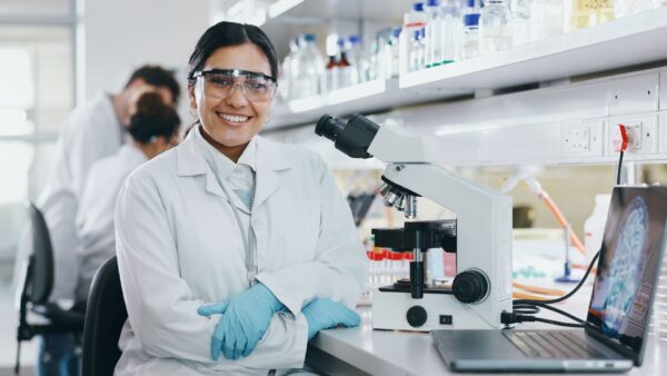 Microscope, scientist and face of medical doctor in goggles
