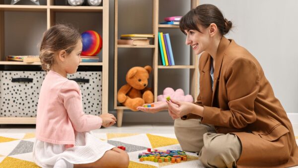 Smiling female psychologist with little girl
