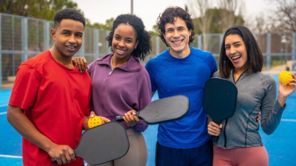 Diverse friends enjoying pickleball on blue court