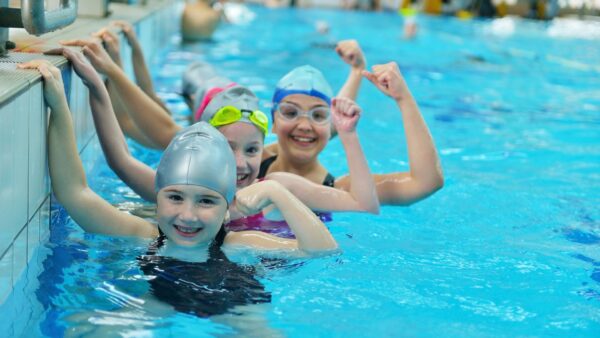 Happy children kids group at swimming pool class learning to swim