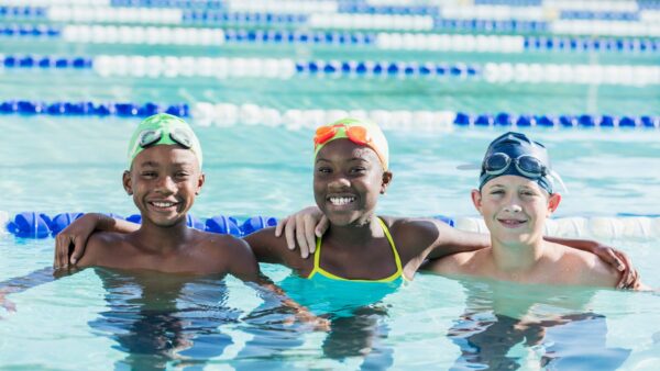 Multi-ethnic children in swimming pool smiling at camera